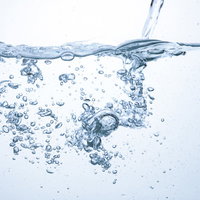 注がれる少量の水と浮かぶ気泡の水中風景の写真