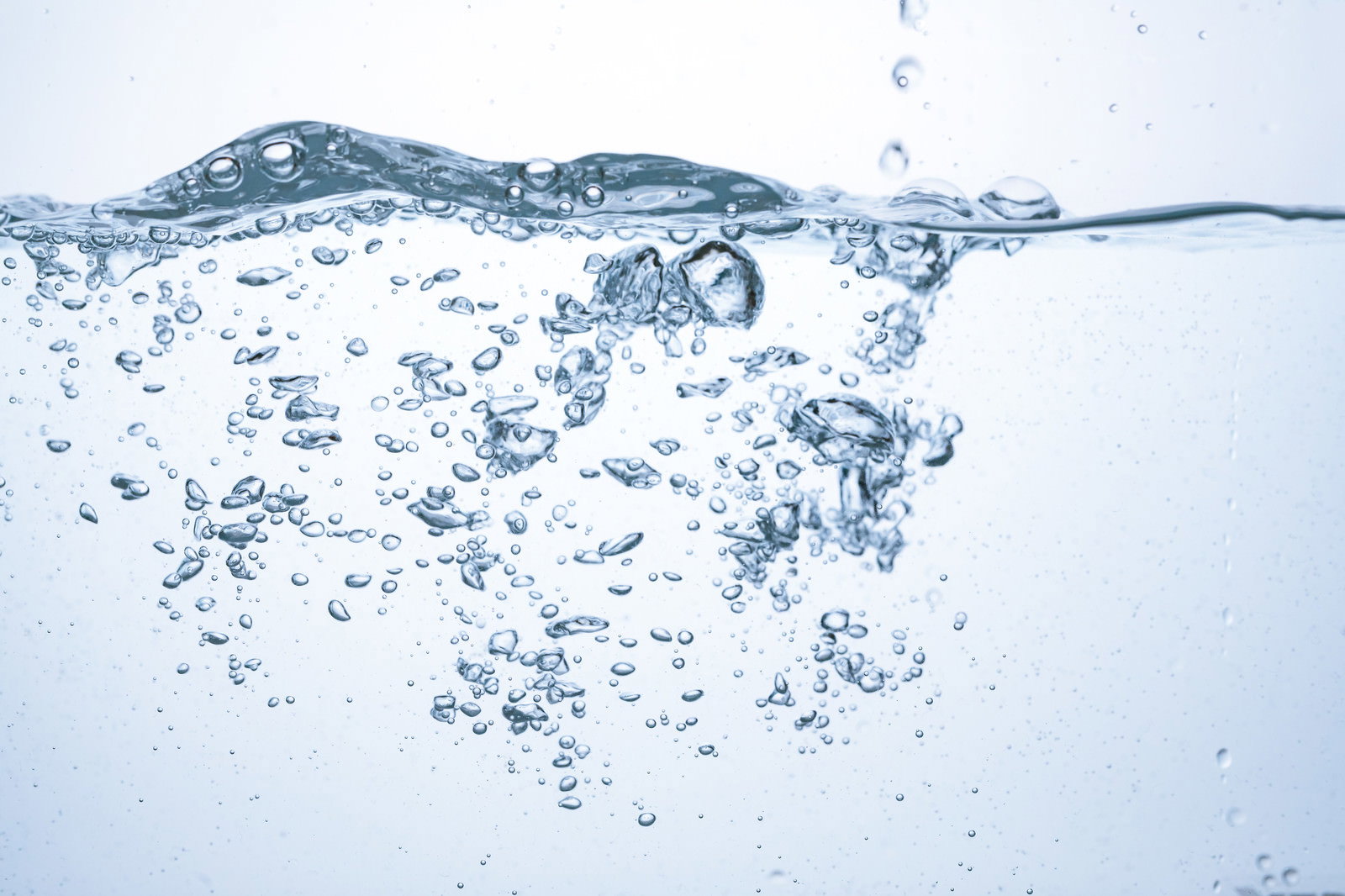 透明な水中で立ち上る細かな気泡と水面の波紋