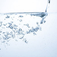 ミネラルウォーターにチョロチョロと注ぐ水と気泡の写真