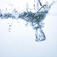 水槽に勢いよく水が注がれ気泡と波紋が広がる瞬間の写真