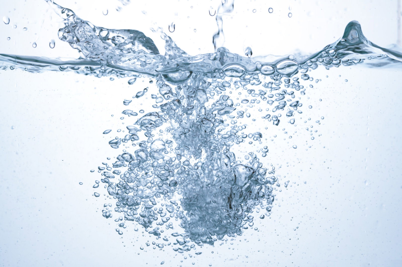 透明な水中に物体が落下し、無数の気泡が勢いよく広がっている様子