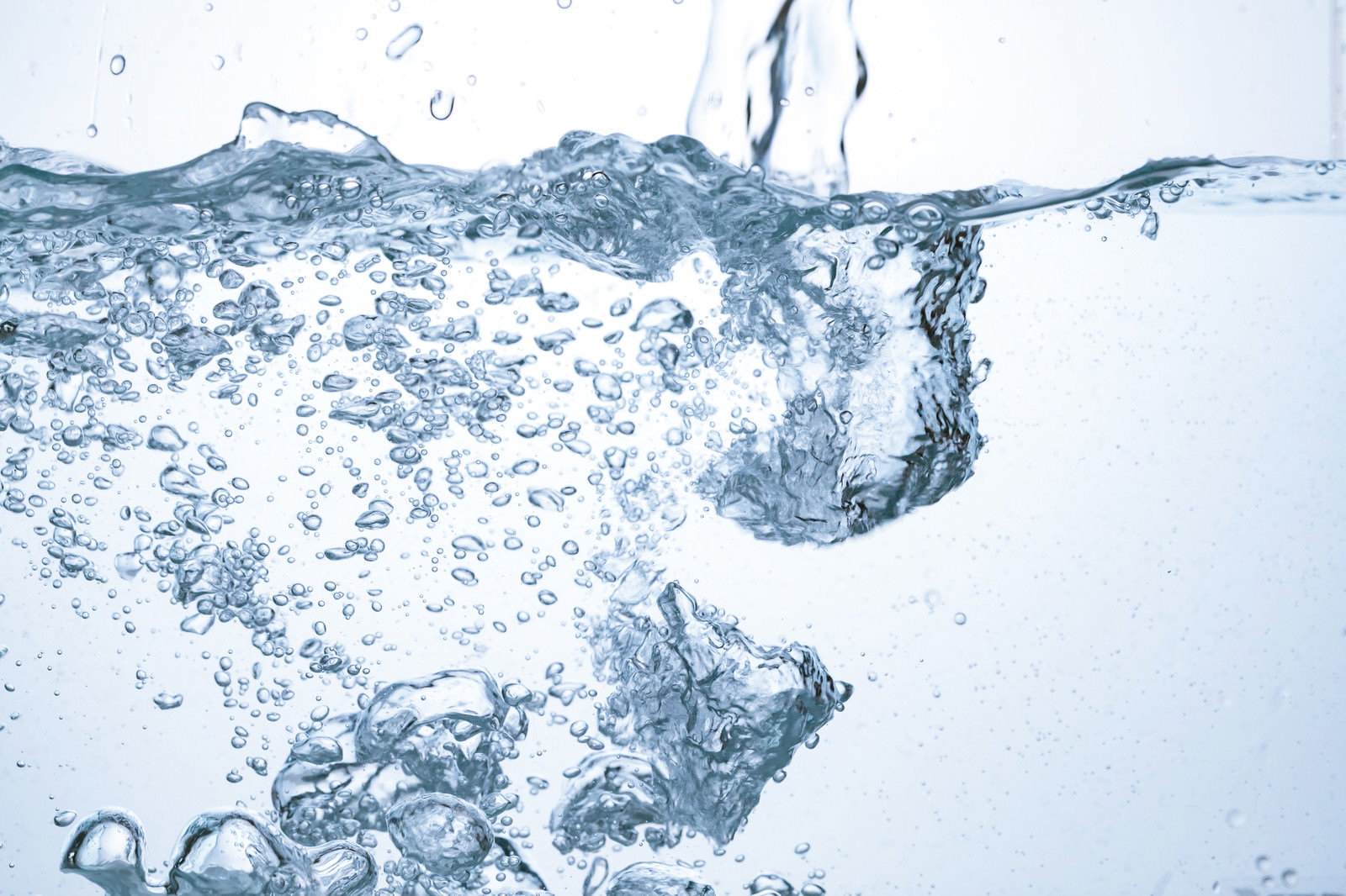 透明な水に氷が落下し、たくさんの気泡が立ち上がっている様子