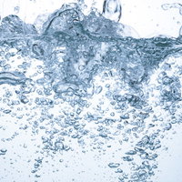 水槽内に勢いよく注がれるミネラルウォーターと気泡の写真
