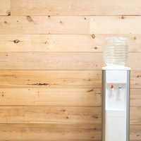 木目調の壁に置かれたウォーターサーバーとミネラルウォーターの写真
