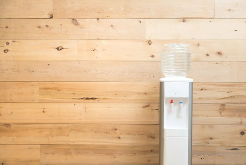 木目調の壁に置かれたウォーターサーバーとミネラルウォーター