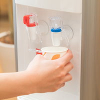 ウォーターサーバーから冷たい水を紙コップに注ぐ手の写真