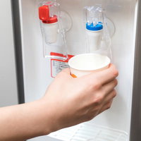 ウォーターサーバーから紙コップに冷たい水を注ぐの写真