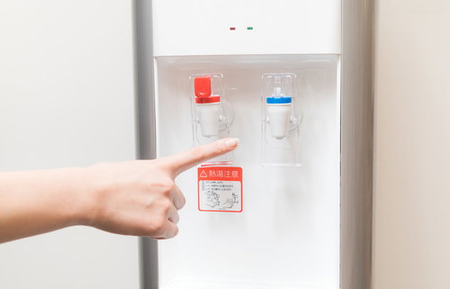 ウォーターサーバーの冷たいボタンを指さす手