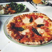 テーブルに置かれた手作りピザ、モッツァレラチーズとバジルのマルゲリータの写真