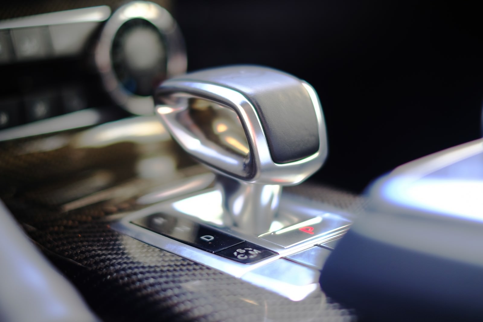 シルバーメタリックな車のシフトノブと黒いコンソール部分