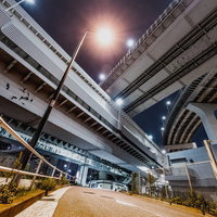 レインボーブリッジ下から見上げた夜景と高速道路の交差の写真