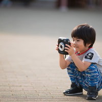 青いシャツを着たインスタントカメラを構えて撮影する子供の写真