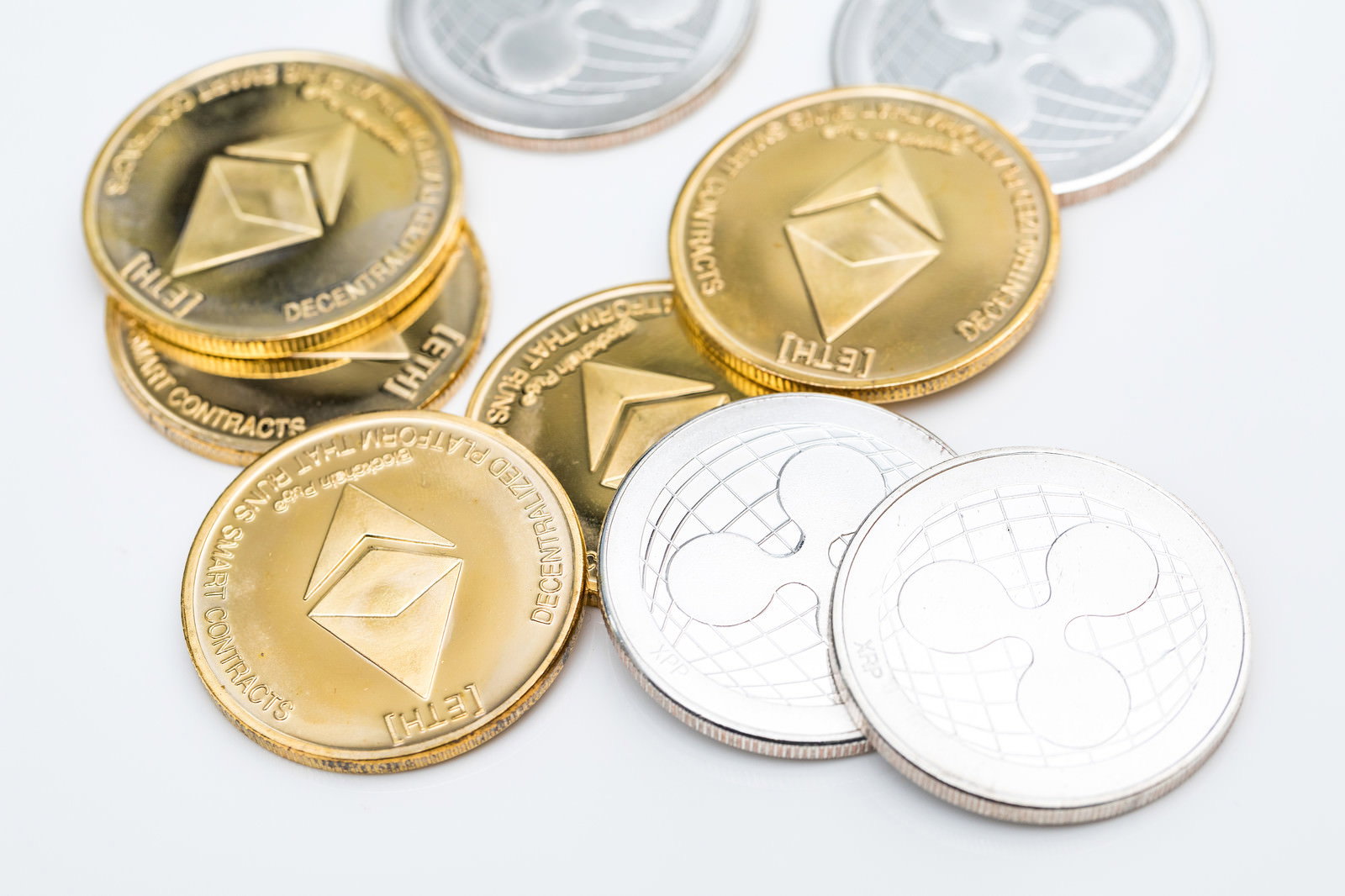 金色と銀色のイーサリアムとリップルのコインが並べられている