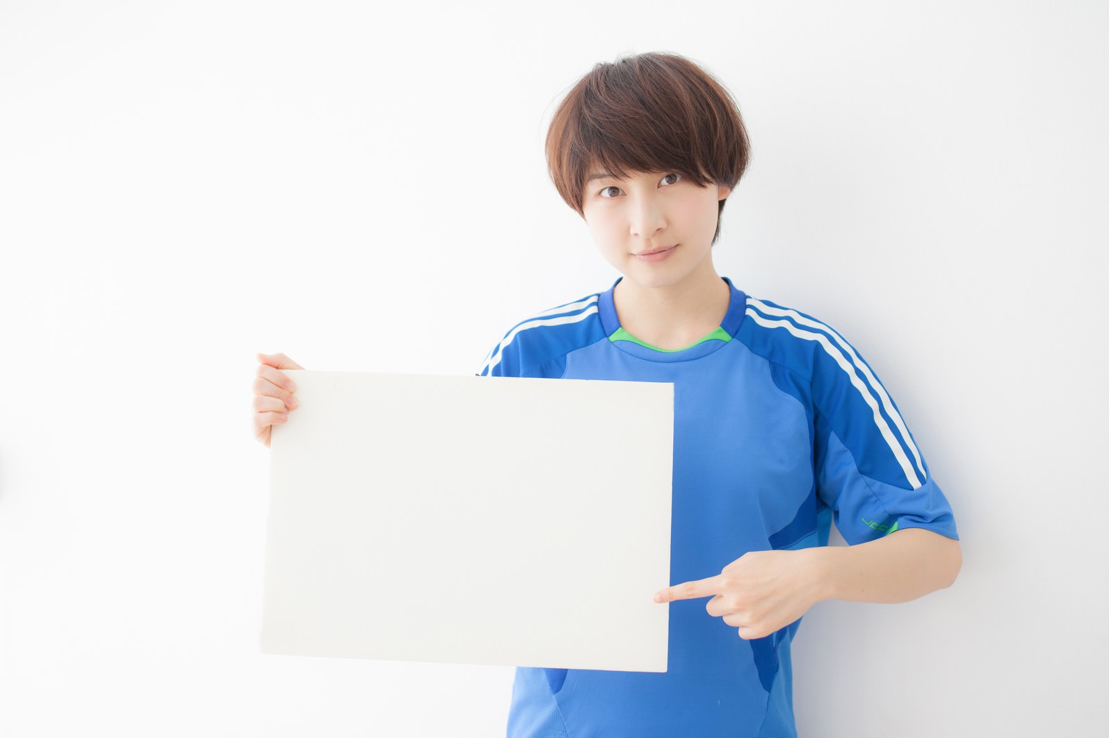 ホワイトボードを指差しながら解説するサッカーユニフォーム姿の女性［モデル：八木彩香］