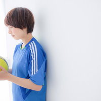 青いユニフォーム姿で黄色いサッカーボールを抱える女子選手の写真