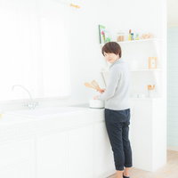 エプロン姿でキッチンで料理をしている若妻の写真