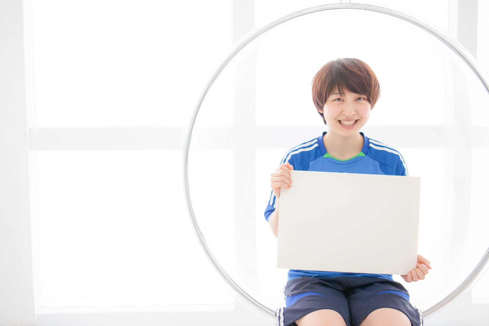 ホワイトボードを持ってW杯までの日数を示す青いユニフォーム姿の笑顔の女性［モデル：八木彩香］