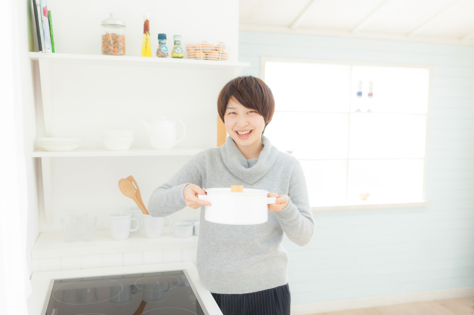 キッチンで朝ごはんのスープが完成し、笑顔で鍋を持つ女性［モデル：八木彩香］