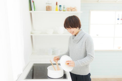 キッチンの IH調理器でスープを温めなおしている女性の写真