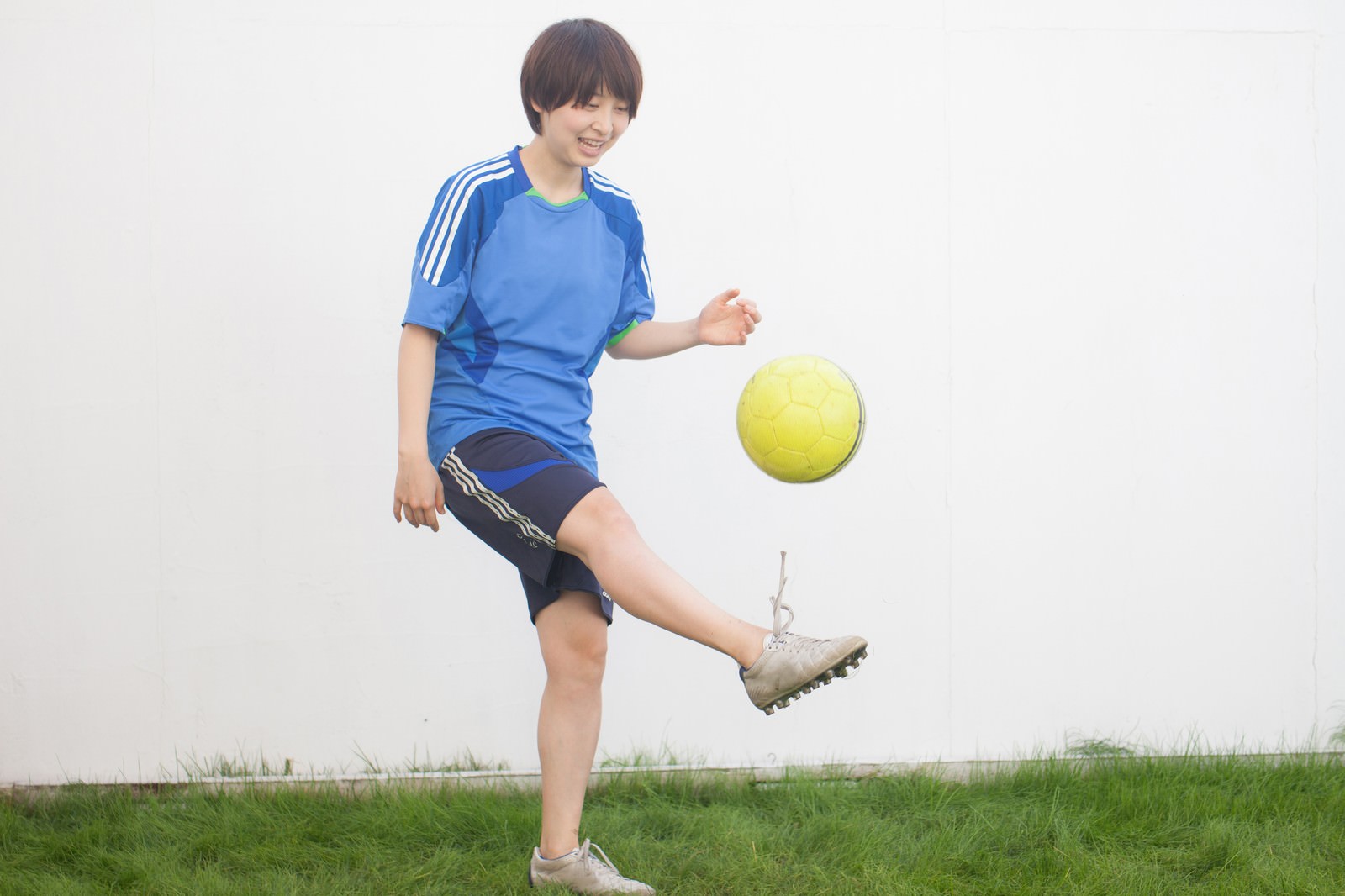 青いユニフォームでリフティング練習する子ども［モデル：八木彩香］