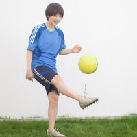 青いユニフォームの女性が黄色いボールをリフティングする練習風景の写真