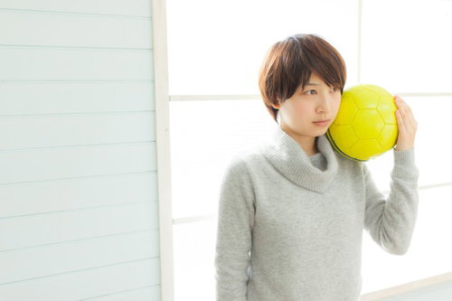 オフシーズンでつまらないサッカー女子、黄色いボールを抱えるの写真