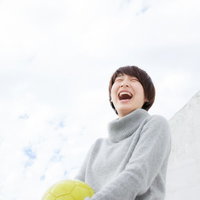 黄色いサッカーボールを抱える女子サッカー部OGの笑顔の写真
