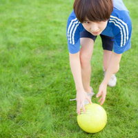 芝生の上でサッカーボールを置く女性アスリートの写真