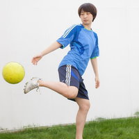 サッカーボールをリフティングでウォームアップする女性の写真