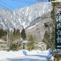 雪に囲まれた平湯温泉の民俗館と北アルプス連峰の写真