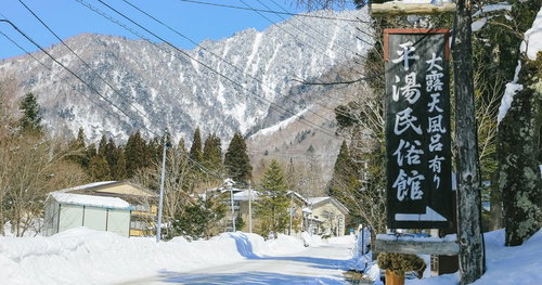 雪に囲まれた平湯温泉の民俗館と北アルプス連峰