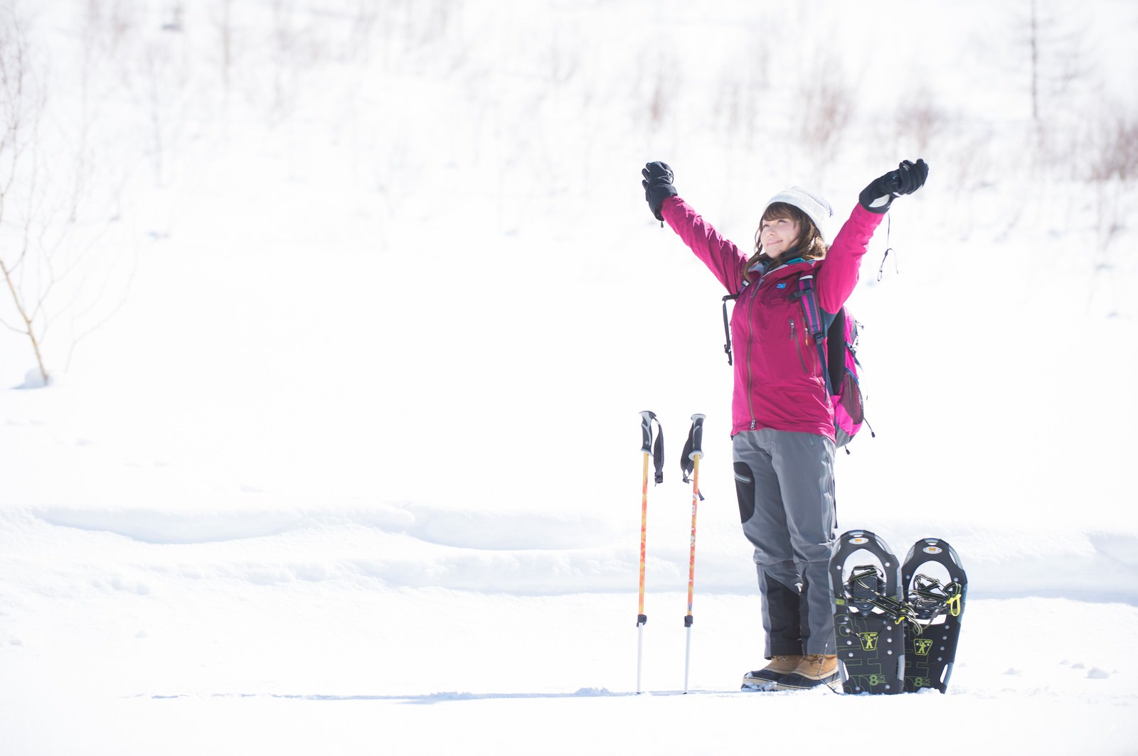 雪山でスノーシューを履き両腕を上げて伸びをする女性［モデル：茜さや］