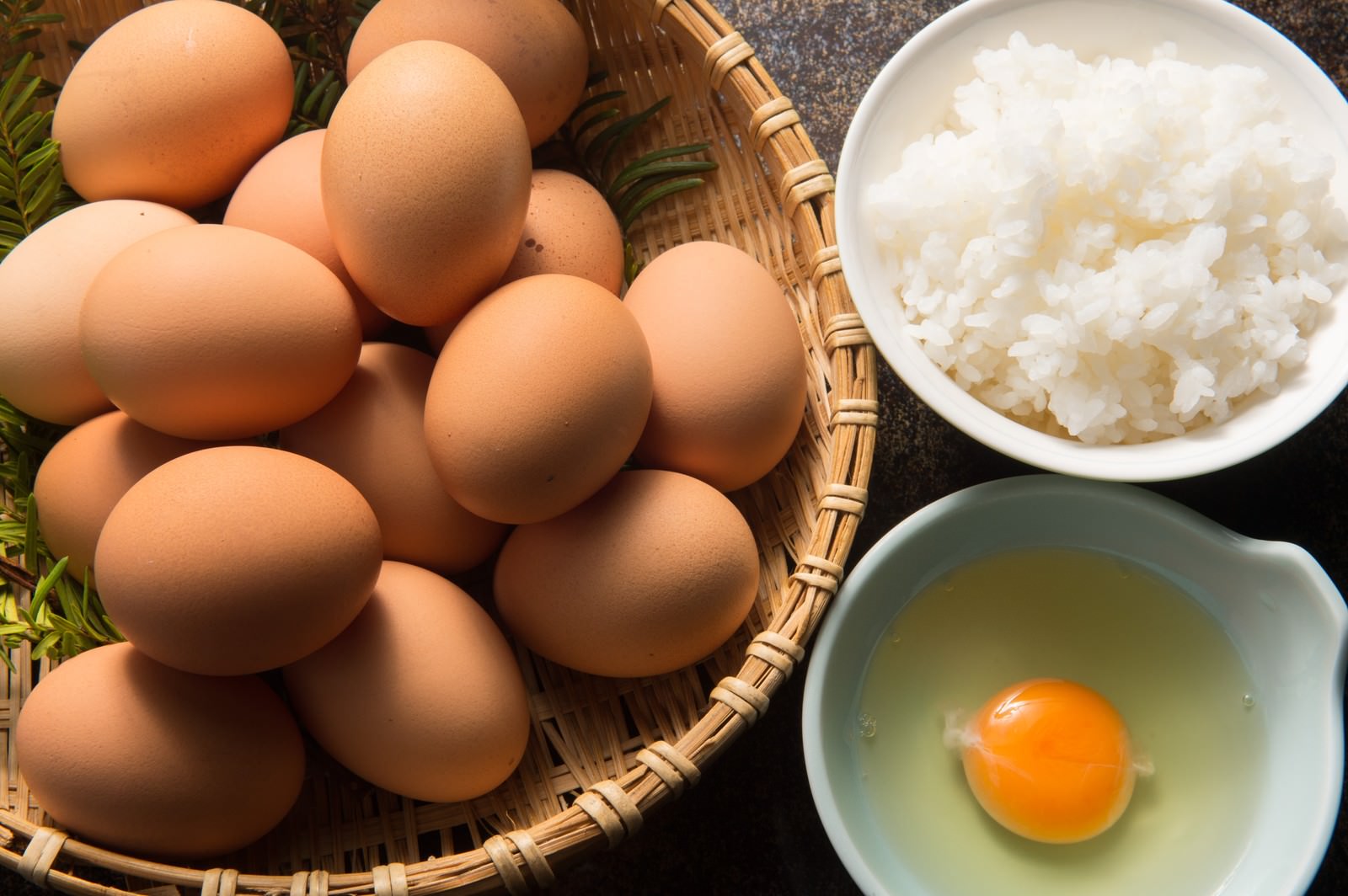 竹かごの卵と白米、生卵を並べた朝食の材料