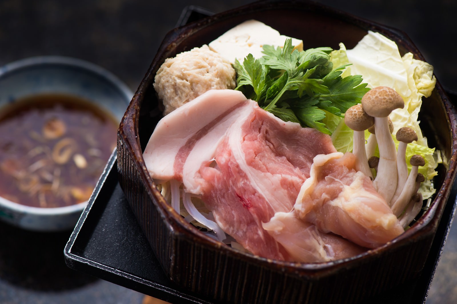 温泉旅館で提供される豚肉と鶏団子のせいろ蒸し料理、タレ付き