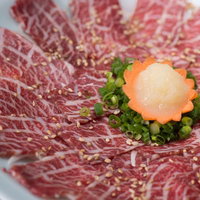 おろしにんにくと刻みネギで食べる霜降り馬刺しの写真