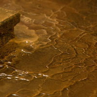 源泉かけ流しの証である波状に溶けた栄太郎の浴場の床の写真