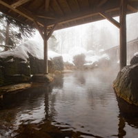雪が降り積もる露天風呂、湯けむりが立ち上る冬の温泉風景の写真