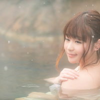 雪が舞う雪見露天風呂で温泉に浸かる女性のくつろぎの写真