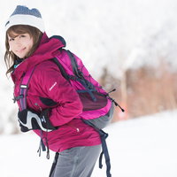 ゲレンデでトレッキングポールを持つ笑顔の女性の写真