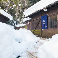 雪深い平湯温泉の施設と足跡を残す男性の冬景色の写真