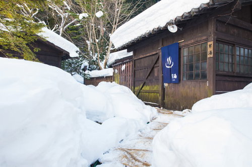 雪深い平湯温泉の施設と足跡を残す男性の冬景色