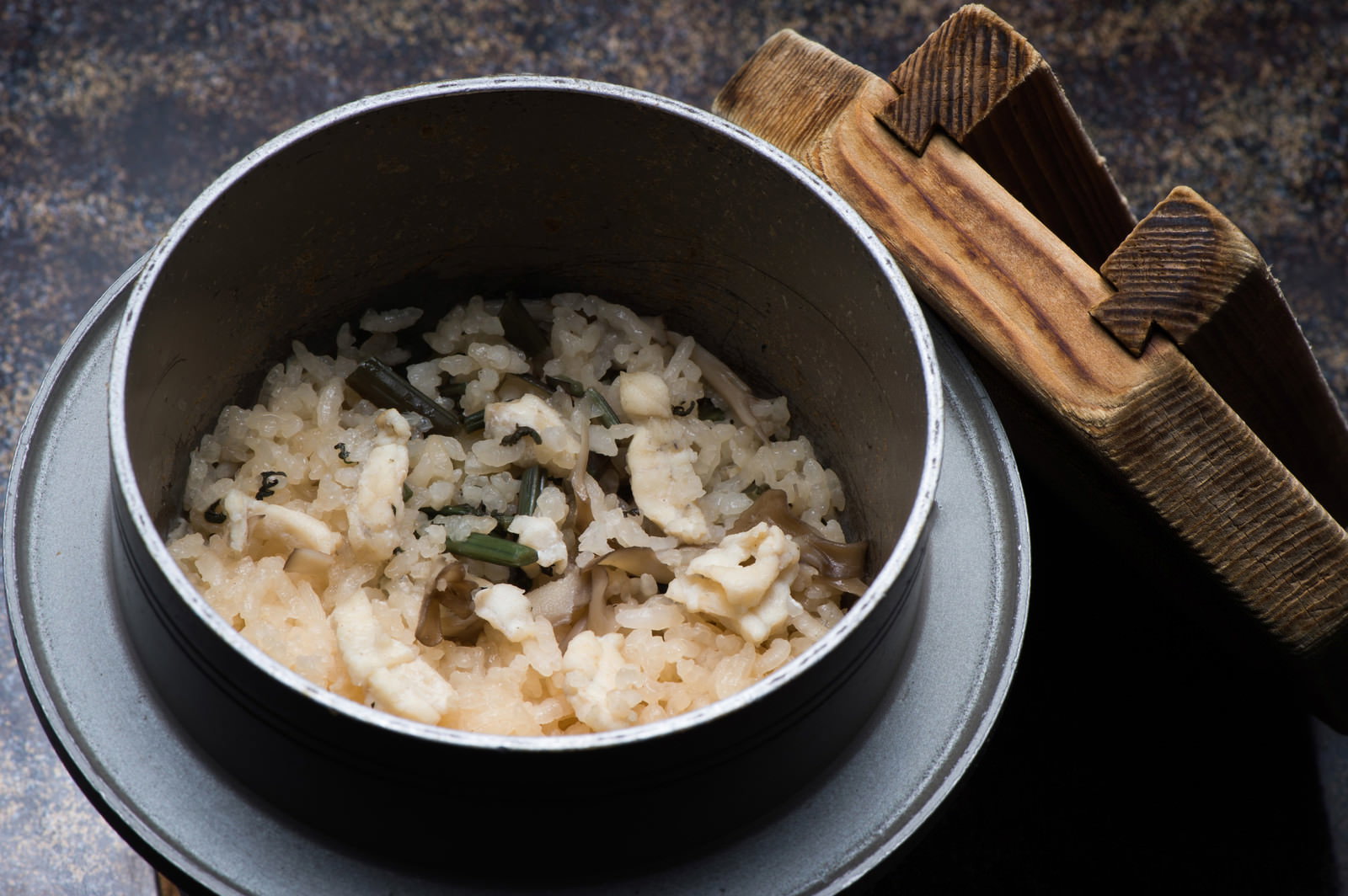 黒い釜に盛られた飛騨ふぐと山菜の炊き込みご飯と木の蓋