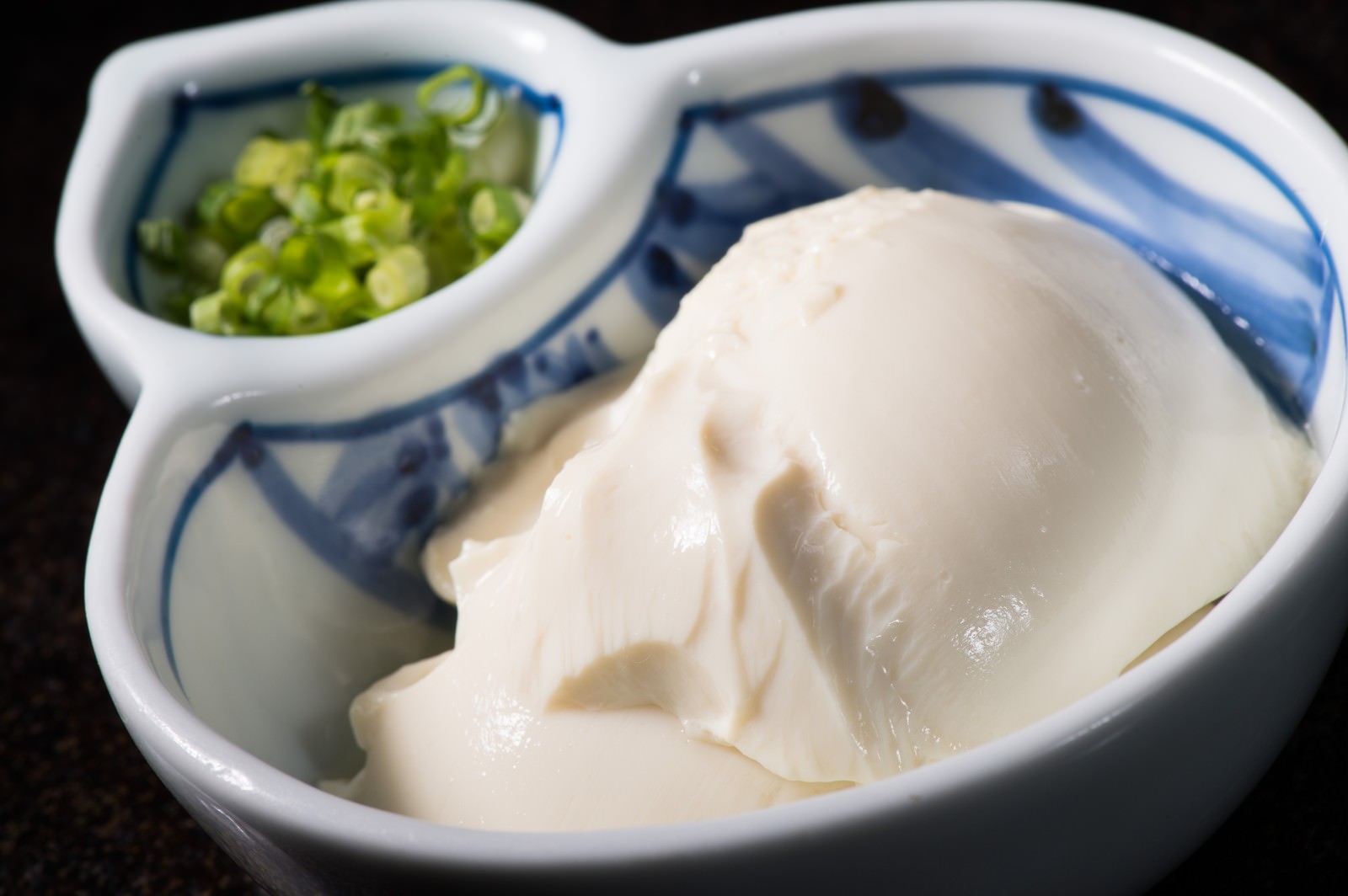 陶器の器に盛られた手作り豆腐と刻みネギ