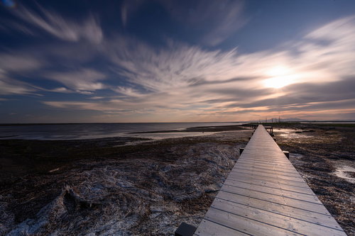 夕暮れ時の野付半島に伸びる木製の桟橋と海岸線