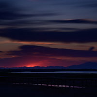 日没時の野付半島、オレンジ色に染まる水平線と木製の桟橋の写真