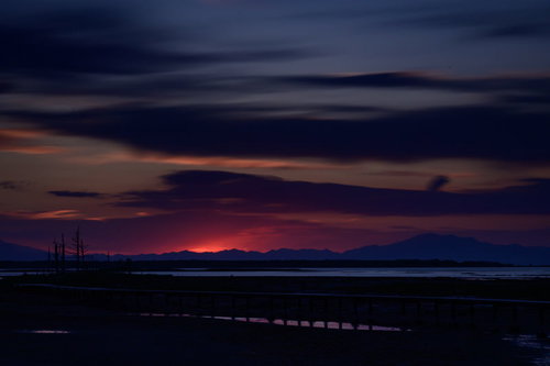 日没時の野付半島、オレンジ色に染まる水平線と木製の桟橋