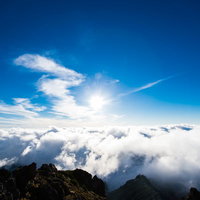 北アルプスの山頂から見る雲海と青空、朝日に照らされた360度の絶景の写真