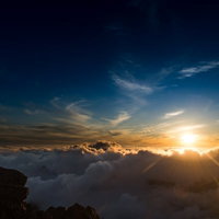 北アルプス山頂から見る夕方の雲海と日没、放射状に降り注ぐ太陽光の写真