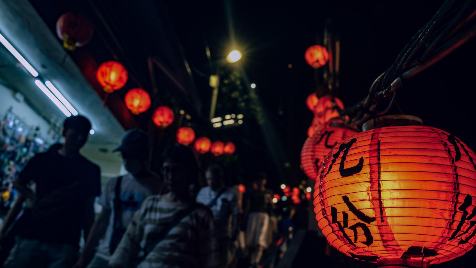 九份の夜間の街路に吊り下がった赤い提灯と歩く人々のシルエット