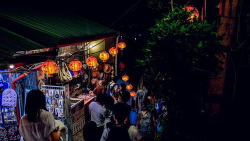 夜間の九份で提灯が灯る商店前に集まる人々